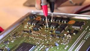 Mersin Abeş Oto Elektrik teknisyeni, kamyon ACM beyin tamiri sırasında elektronik devre kartını dikkatle inceliyor ve onarıyor.